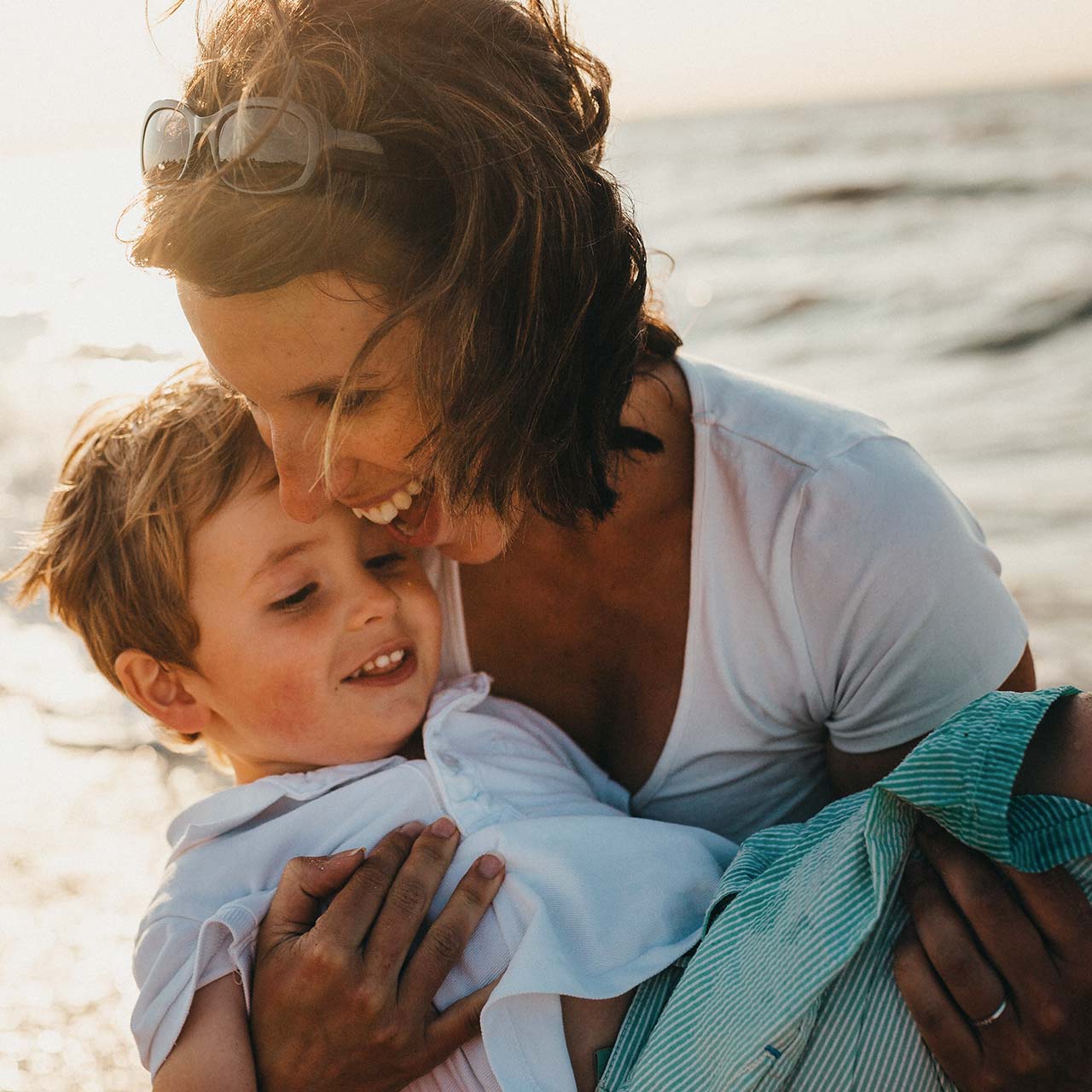 Happy mother with child in her arms at the beach